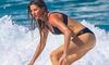 Gisele Bündchen rides a wave and shows off her body